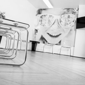 Modernes, helles Wartezimmer mit Glasstühlen und großem Wandbild eines lachenden Kindes.