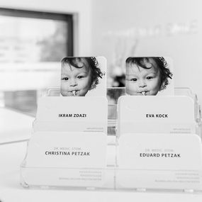 Visitenkartenständer in moderner Zahnarztpraxis mit Kinderfoto und Zahnarztnamen.