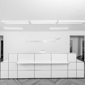 Heller Empfangsbereich einer modernen Zahnarztpraxis mit minimalistischer Einrichtung.